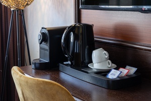 Hotel room in Amrâth Hotel DuCasque with a desk, flat-screen TV, coffee and tea facilities, and a view of the adjacent bathroom with a washbasin.