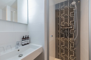 Modern bathroom in Amrâth Hotel DuCasque with walk-in shower, toilet, washbasin, and black tiled wall with a pattern.