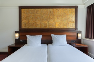 Deluxe kamer in Amrâth Hotel DuCasque met tweepersoonsbed, warme kleuren, zithoek en natuurlijk licht.