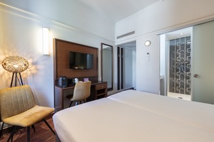 Moderne hotelkamer in Amrâth Hotel DuCasque met tweepersoonsbed, bureau, flatscreen-tv en zithoek bij het raam.
