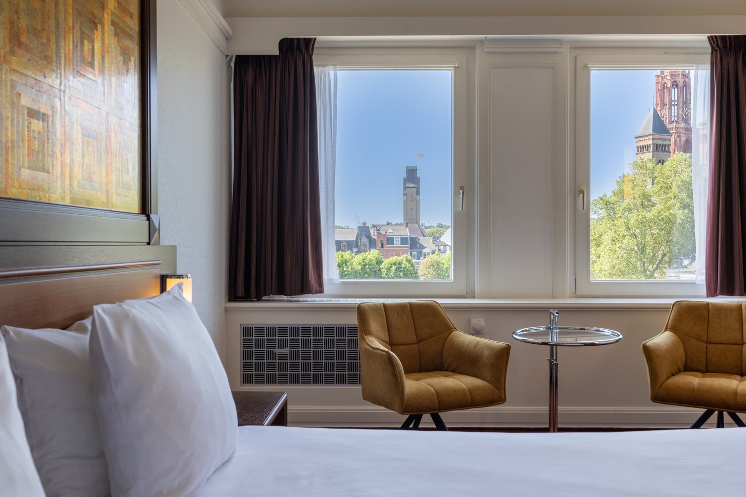  Deluxe hotelkamer van Amrâth Hotel DuCasque met tweepersoonsbed, warm kleurgebruik en moderne inrichting.