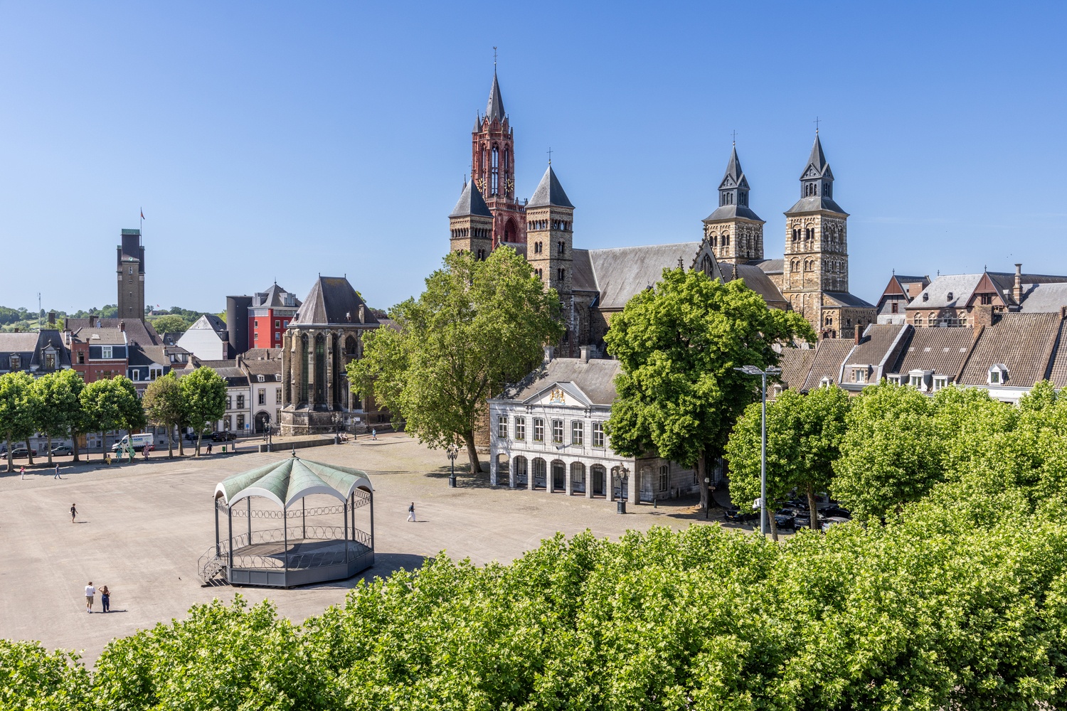 Uitzicht vanaf balkon op het Vrijthof in Maastricht met fietsen, kraampjes en de Sint-Servaasbasiliek op de achtergrond.