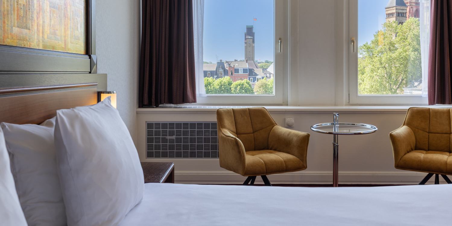 Deluxe kamer in Amrâth Hotel DuCasque met tweepersoonsbed, warme kleuren, zithoek en natuurlijk licht.