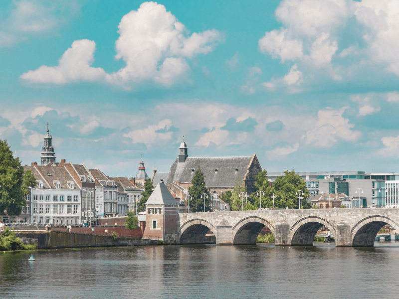 The Vrijthof in Maastricht at twilight, with the Basilica of Saint Servatius and the red tower of Saint John's Church in the background, and a music pavilion on the square in front of it.