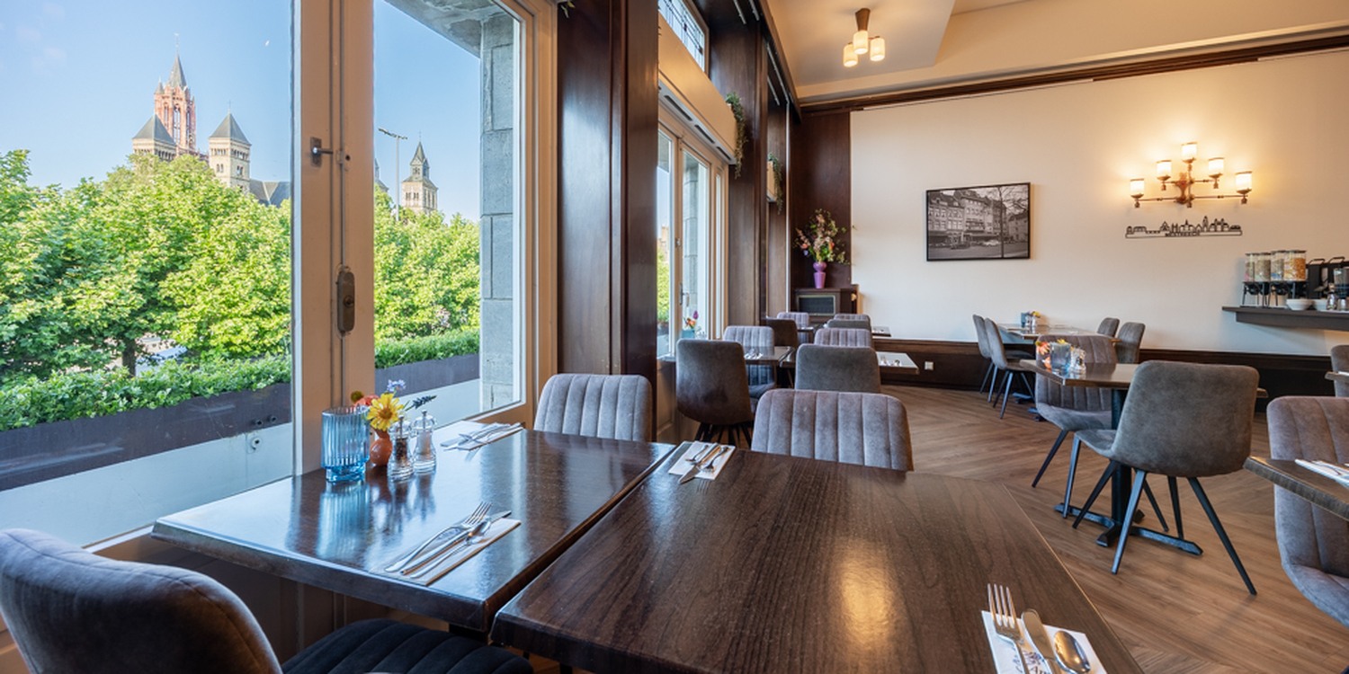 Gedeckter Tisch mit Blumenvase im Restaurant des Amrâth Hotel DuCasque, mit Blick auf den Vrijthof in Maastricht.